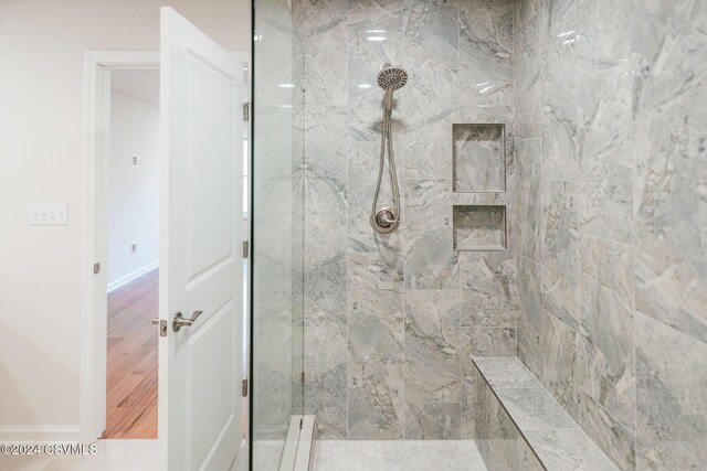 bathroom featuring baseboards and a marble finish shower