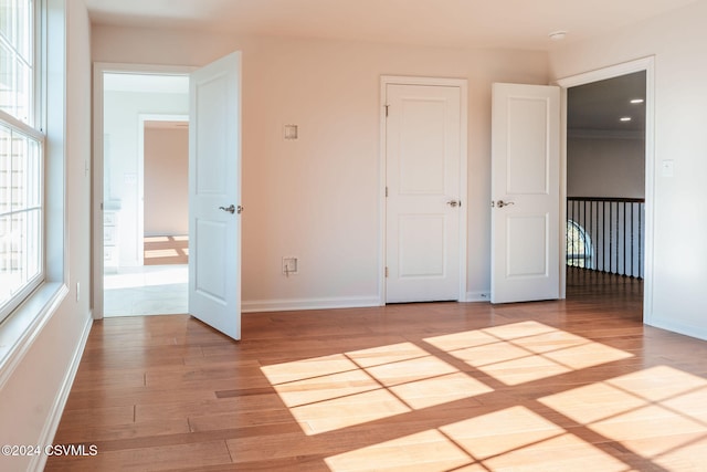 unfurnished bedroom with multiple windows and light wood-type flooring