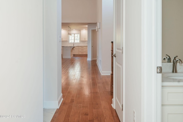 hall with a sink and light wood finished floors