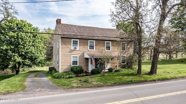 colonial-style house featuring a front lawn