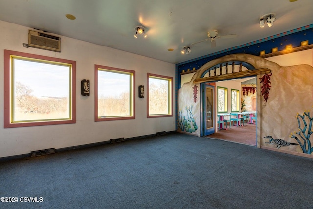 carpeted spare room with an AC wall unit and ceiling fan