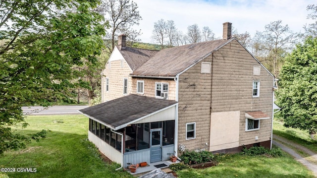 rear view of property with a lawn and a sunroom