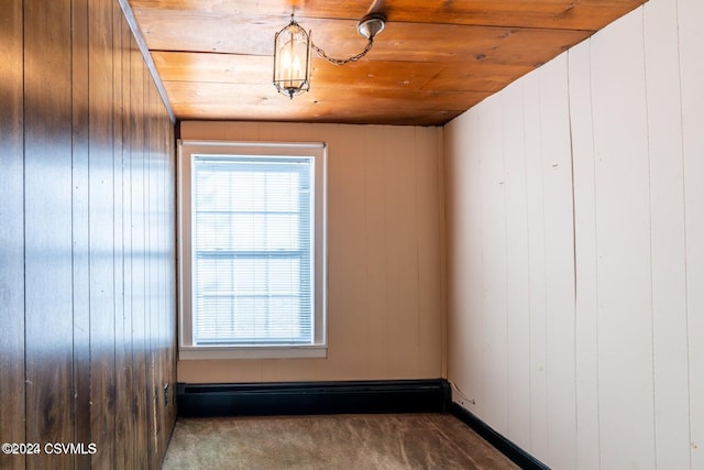 carpeted spare room with wooden walls and wooden ceiling