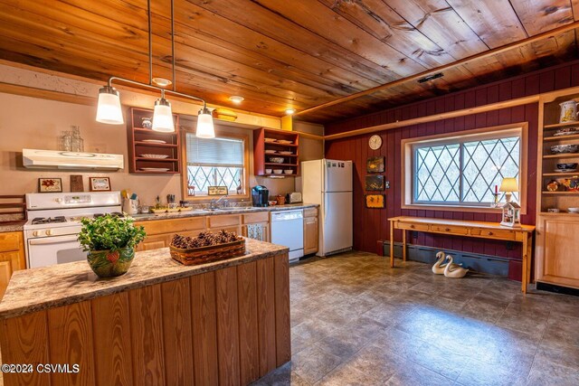 kitchen featuring white appliances, wood walls, wooden ceiling, decorative light fixtures, and light stone counters