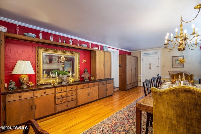 dining space with crown molding, light hardwood / wood-style flooring, and a chandelier