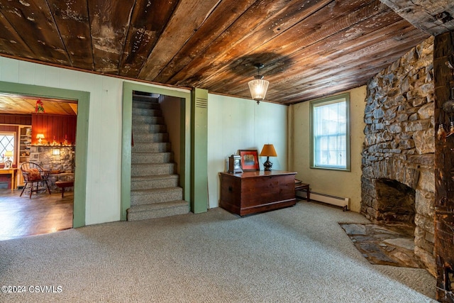 basement with baseboard heating, a stone fireplace, carpet flooring, and wooden ceiling