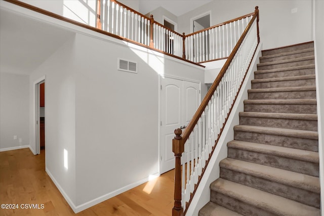 staircase with hardwood / wood-style flooring and a towering ceiling