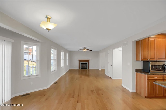 unfurnished living room featuring ceiling fan and light hardwood / wood-style flooring