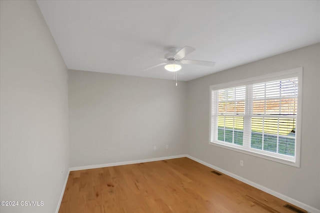 empty room with ceiling fan and light hardwood / wood-style flooring