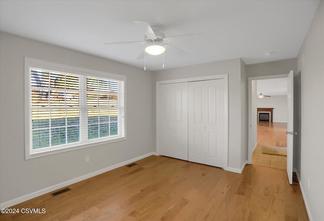 unfurnished bedroom with light hardwood / wood-style floors, ceiling fan, and a closet