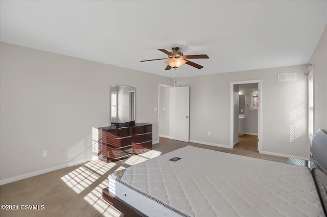 bedroom featuring connected bathroom, light colored carpet, and ceiling fan