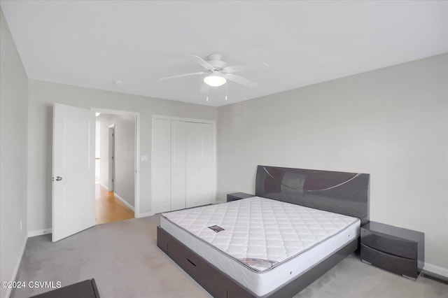 bedroom featuring a closet, light colored carpet, and ceiling fan