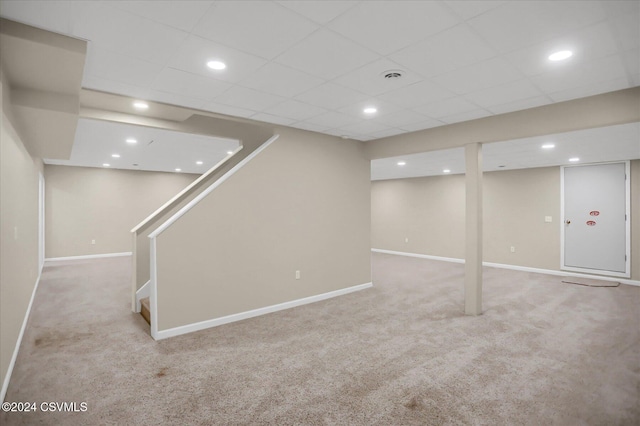 basement with a drop ceiling and light carpet