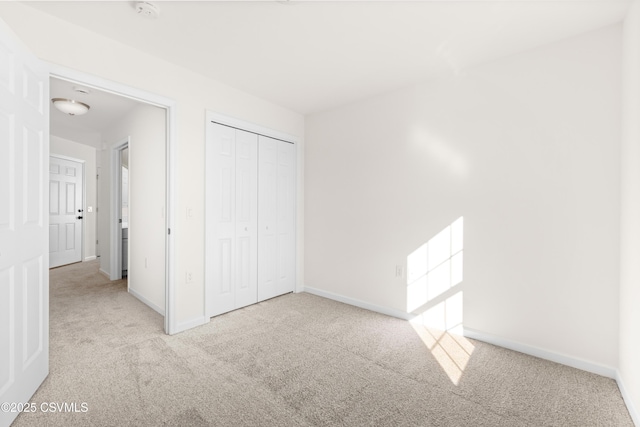 unfurnished bedroom featuring light carpet and a closet