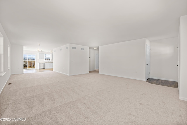 unfurnished living room featuring light colored carpet and a chandelier