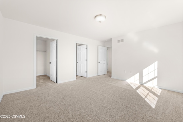 unfurnished bedroom with light carpet, a spacious closet, and a closet