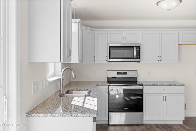 kitchen featuring dark wood-type flooring, sink, white cabinetry, stainless steel appliances, and light stone countertops