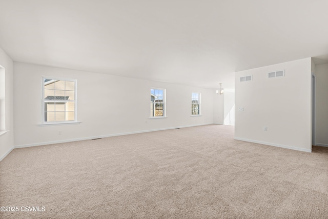 carpeted spare room with a healthy amount of sunlight and an inviting chandelier