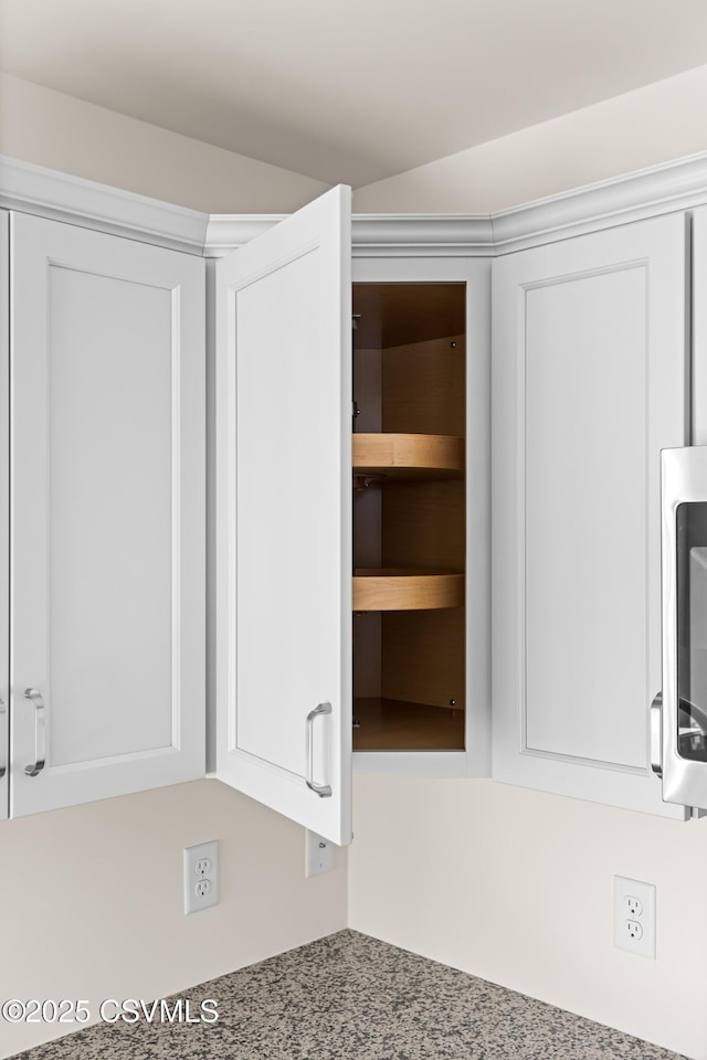 interior details featuring white cabinetry and light stone counters