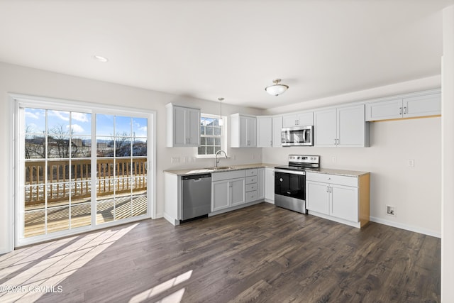 kitchen with pendant lighting, sink, dark wood-type flooring, white cabinetry, and stainless steel appliances