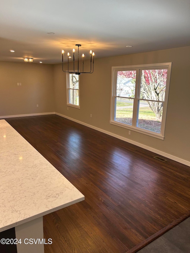 unfurnished dining area with dark hardwood / wood-style floors and an inviting chandelier