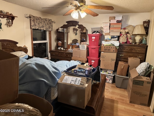 bedroom with a textured ceiling, ceiling fan, and light wood-type flooring