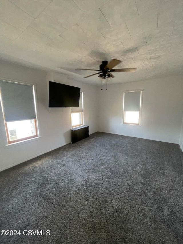 unfurnished room featuring radiator heating unit, plenty of natural light, and carpet floors