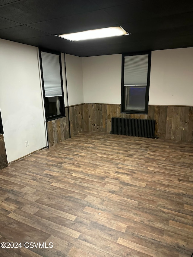 unfurnished room with radiator, wooden walls, and hardwood / wood-style floors