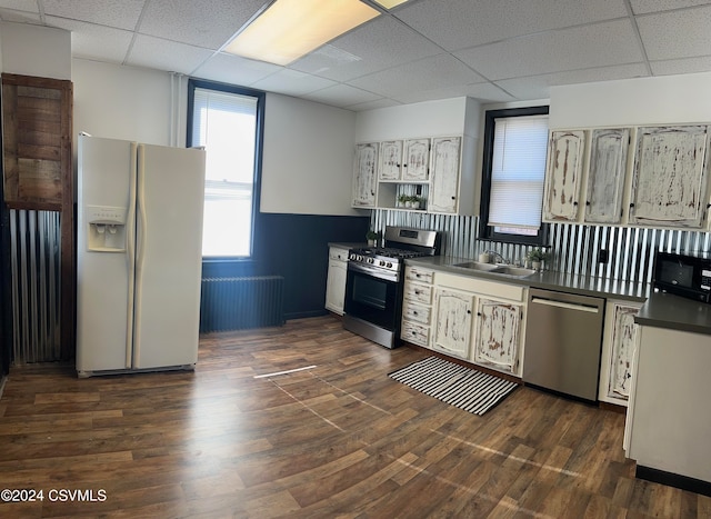 kitchen featuring a drop ceiling, radiator heating unit, stainless steel appliances, and dark hardwood / wood-style flooring