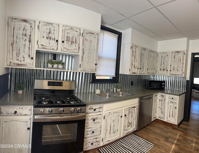 kitchen featuring dark wood-type flooring, stainless steel appliances, backsplash, sink, and a paneled ceiling