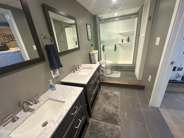 bathroom featuring a paneled ceiling, toilet, a shower with shower door, vanity, and tile patterned floors