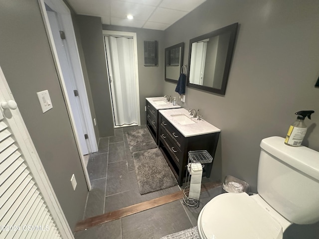 bathroom featuring toilet, a drop ceiling, vanity, and tile patterned flooring