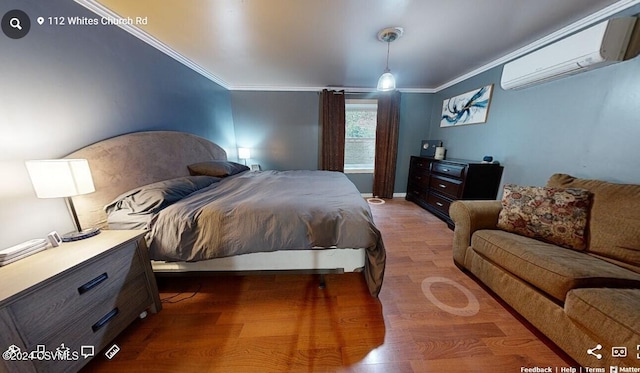 bedroom with ornamental molding, a wall unit AC, and wood-type flooring