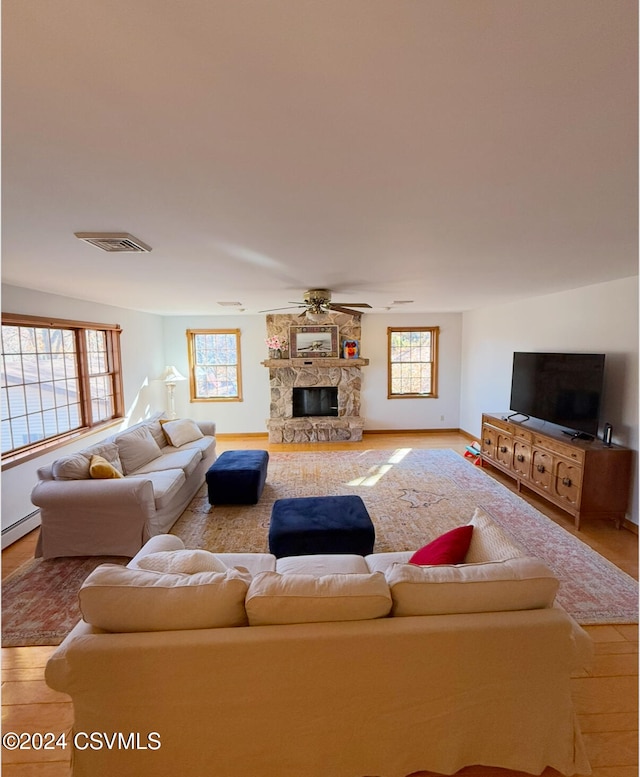 living room with a fireplace, plenty of natural light, light hardwood / wood-style floors, and ceiling fan