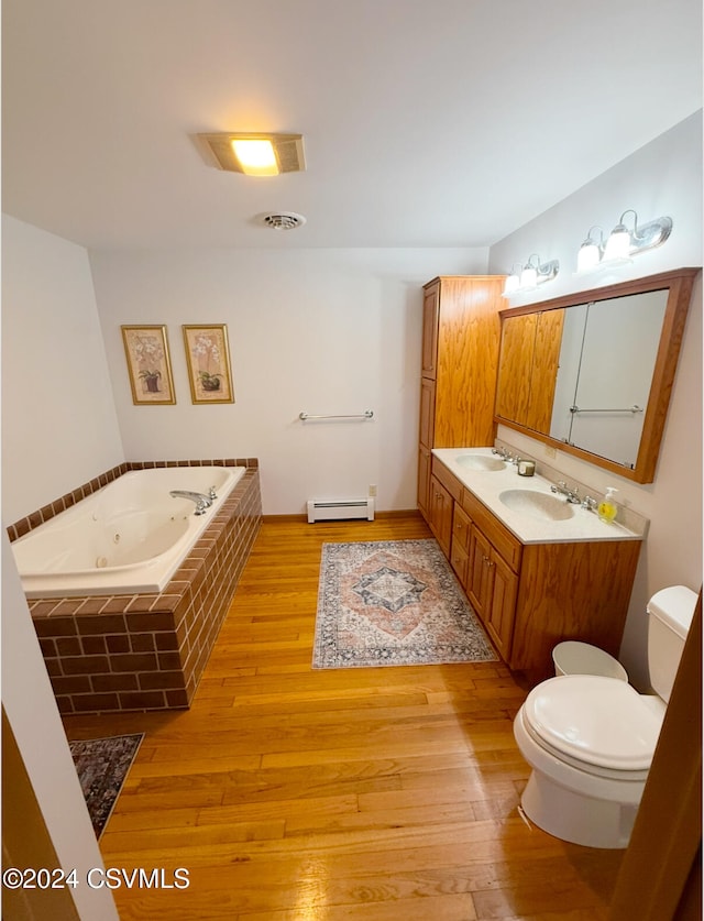 bathroom featuring tiled bath, vanity, hardwood / wood-style flooring, a baseboard heating unit, and toilet