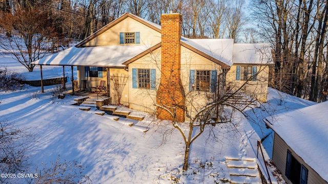 snow covered back of property with a porch