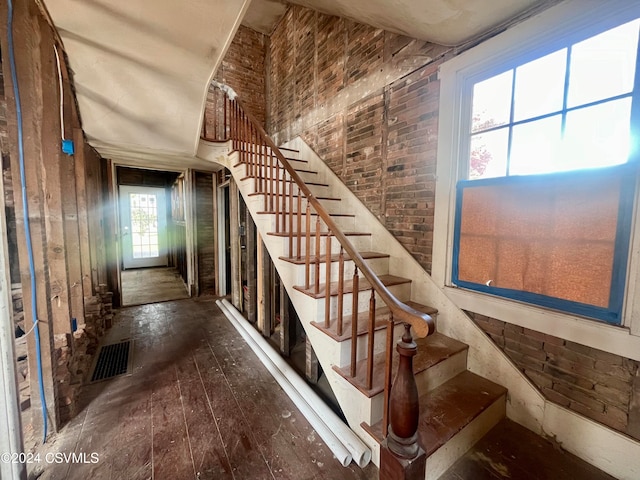 stairs with hardwood / wood-style floors and a healthy amount of sunlight