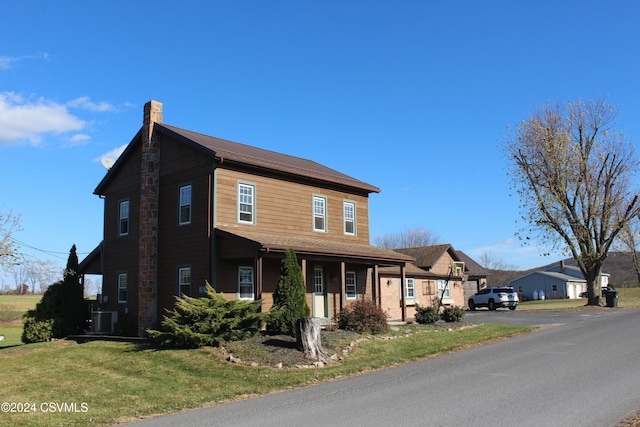 view of front of home featuring cooling unit and a front yard