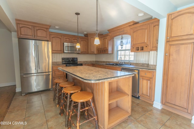 kitchen featuring stainless steel appliances, a center island, light tile patterned floors, sink, and pendant lighting