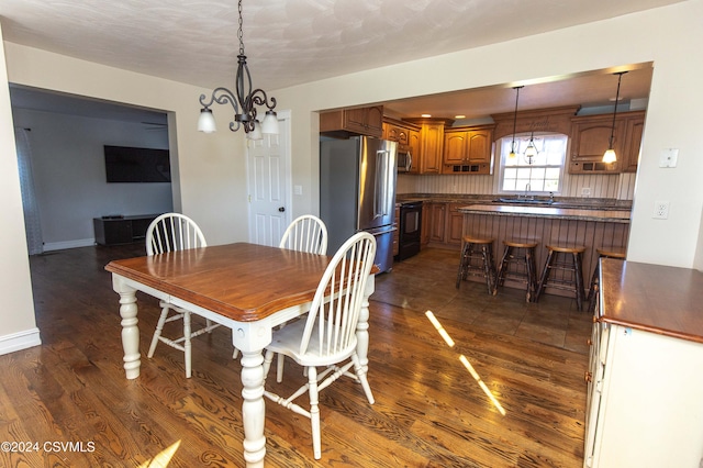 dining area featuring dark wood-type flooring, sink, and a chandelier