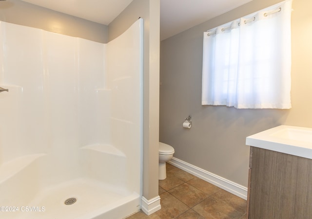 bathroom featuring vanity, tile patterned floors, toilet, and a shower