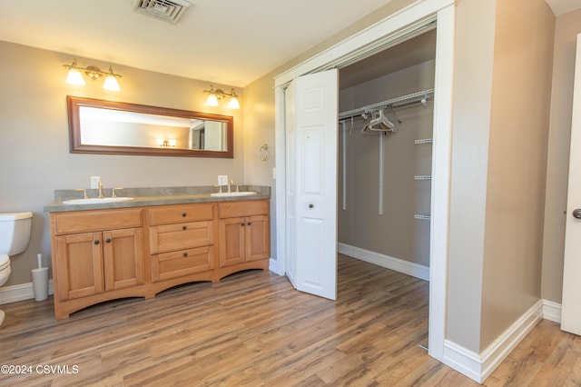 bathroom with toilet, vanity, and wood-type flooring