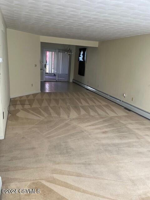 carpeted spare room featuring a baseboard radiator