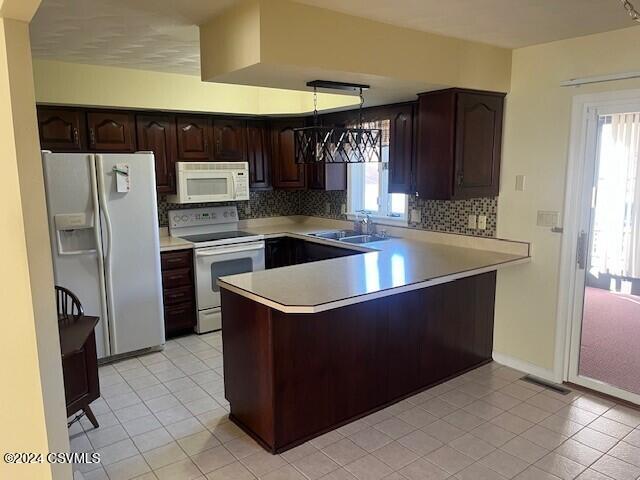 kitchen featuring kitchen peninsula, light tile patterned floors, backsplash, white appliances, and pendant lighting