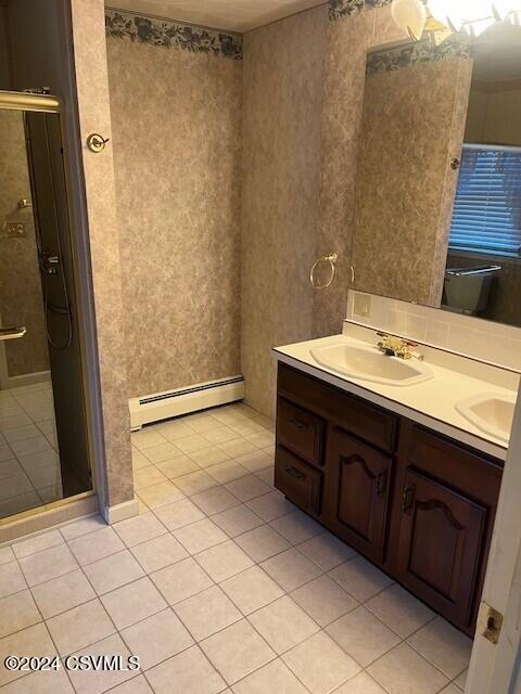 bathroom with baseboard heating, tile patterned flooring, walk in shower, and vanity