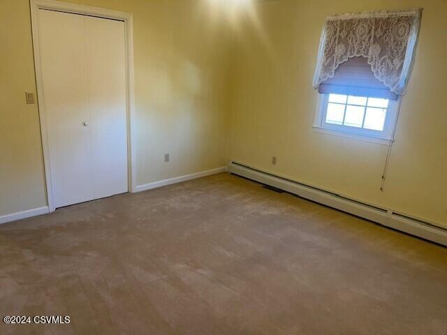 spare room featuring light carpet and baseboard heating