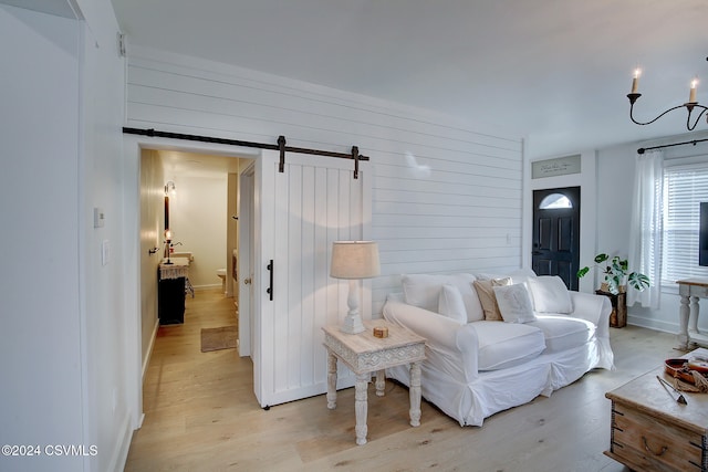 living room with a barn door, a notable chandelier, and light hardwood / wood-style floors