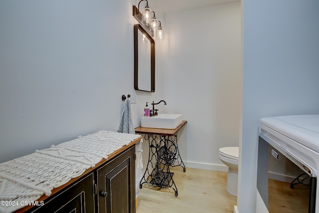 bathroom featuring hardwood / wood-style floors, washer / dryer, sink, and toilet