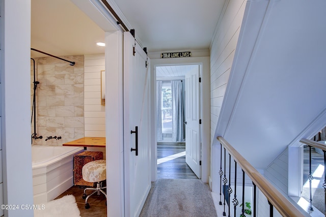 corridor with a barn door, hardwood / wood-style flooring, and crown molding