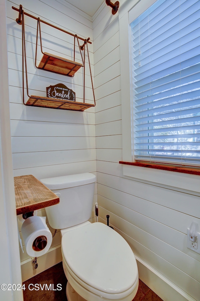 bathroom featuring wood walls and toilet